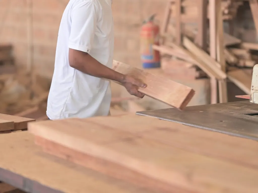 A craftsman feeding a wood plank through a table saw on the Wood Factory production floor