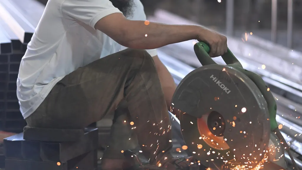 A craftsman cutting a steel furniture frame on the Wood Factory workshop floor, Jodhpur
