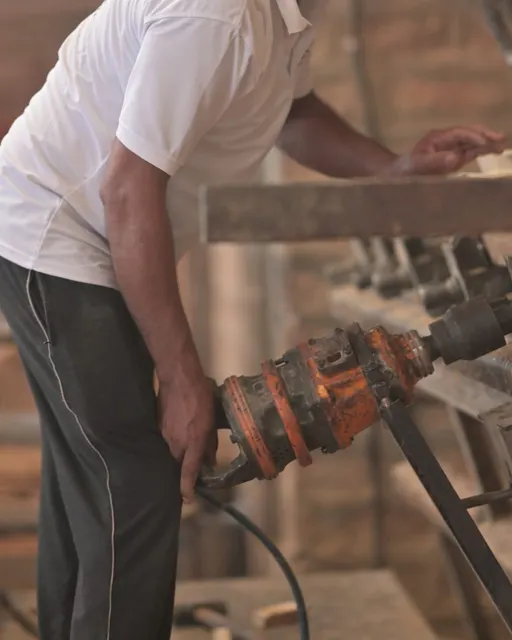 A craftsman joining wood planks together under high pressure at Wood Factory